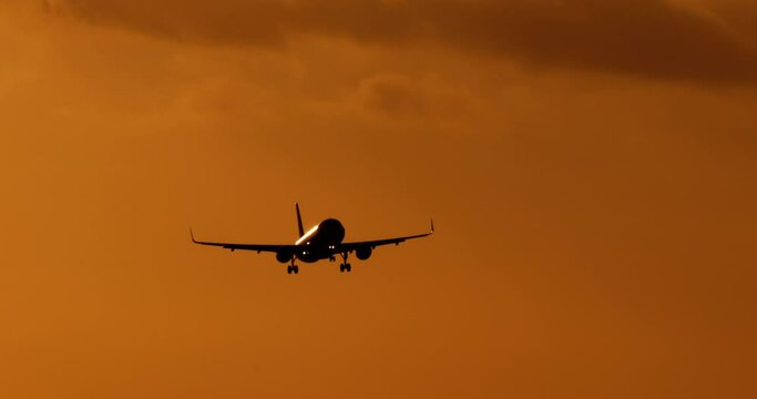 Sunset in orange tones and colors and dark silhouette of commercial passenger plane in flight. Provision of transport services by airline for tourists and travelers. Air transportation of passengers