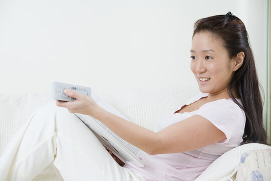 Young woman using a TV remote control