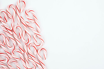 Pile of red and white candy canes on white background with open space. top view