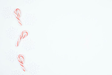 top view Frame of Candy canes and snowflakes on white background