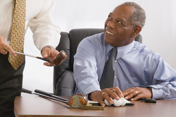 Mid section view of a businessman holding a golf club with another businessman looking at him and smiling