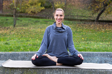woman meditating in public park during autumn