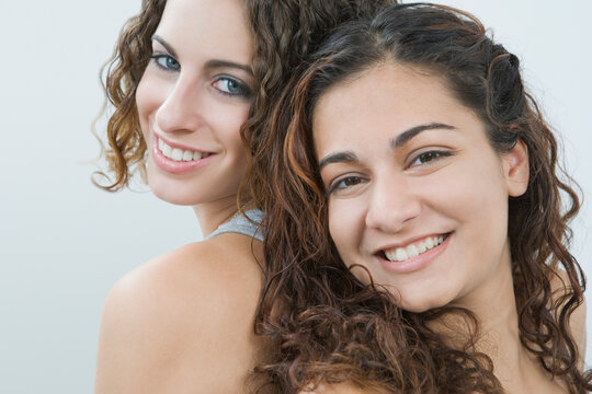 Portrait of two teenage girls smiling back to back