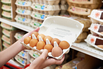 Hands with packages of eggs in store