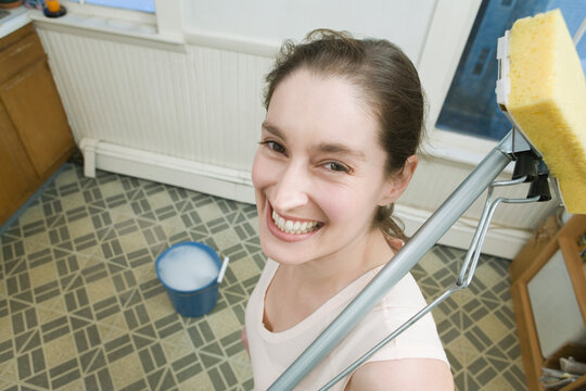 Portrait of a mid adult woman holding a mop and smiling
