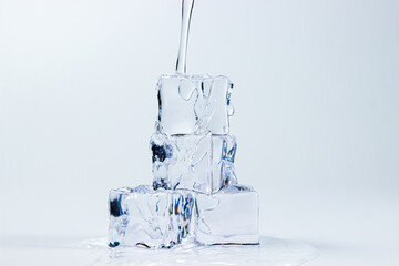Water pours on ice cubes on a white background.