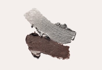Smeared metallic brown and silver liquid eye shadow or gel eye liner textures smudge isolated on beige
