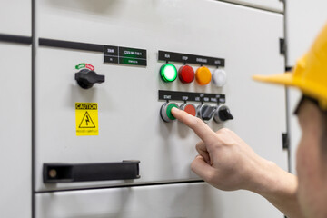 Engineer's finger is pressing a button to test a system in front of a control panel in an...