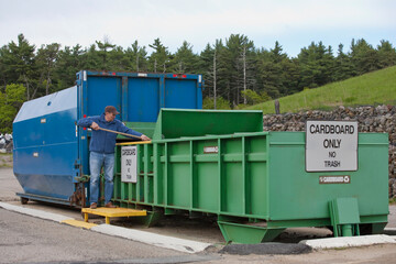 Engineer arranging cardboard at Cardboard Only recycling compactor connected to container