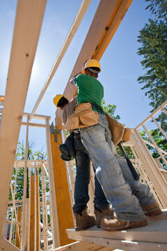 Carpenters lifting a laminated beam at a construction site