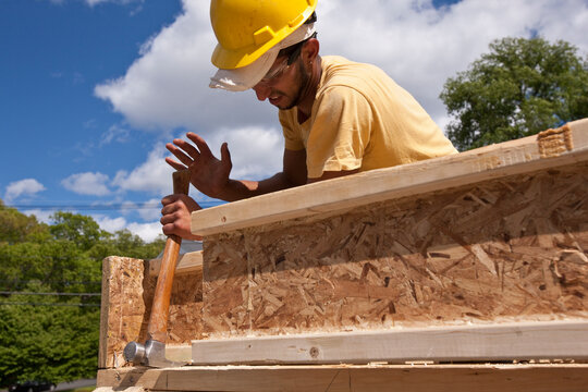 Carpenter using framing hammer on a house frame