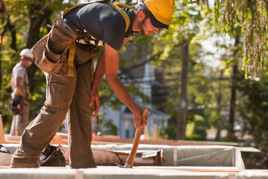 Carpenter using a claw hammer at a construction site