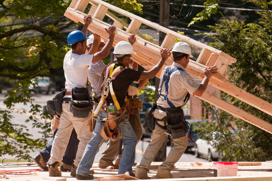 Carpenters lifting roofing gable frame at a construction site