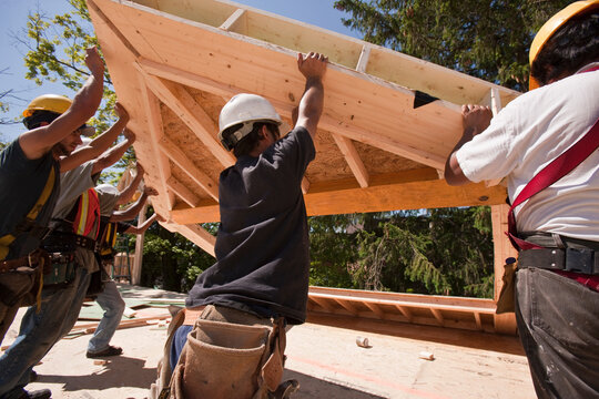 Carpenters lifting roofing gable frame at a construction site