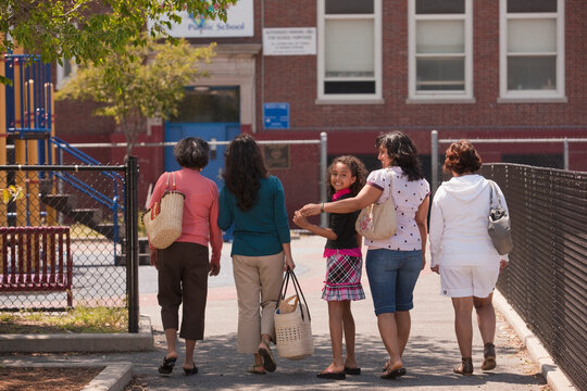 A group of women over three generations walking together in a row down an outdoor walkway