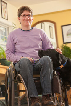 Woman with multiple sclerosis in a wheelchair stroking her service dog