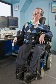 Businessman with Duchenne muscular dystrophy using a breathing ventilator in an office