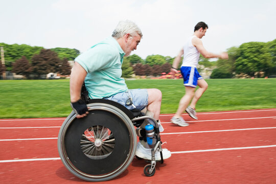 Young man racing with a handicapped senior man on a racetrack.