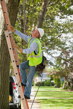 Lineman climbing a ladder to work on wires