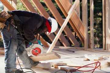 Carpenter cutting bevel on rafter with a circular saw
