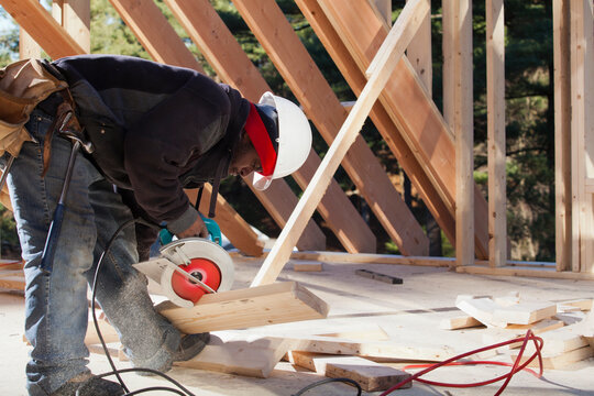 Carpenter cutting bevel on rafter with a circular saw