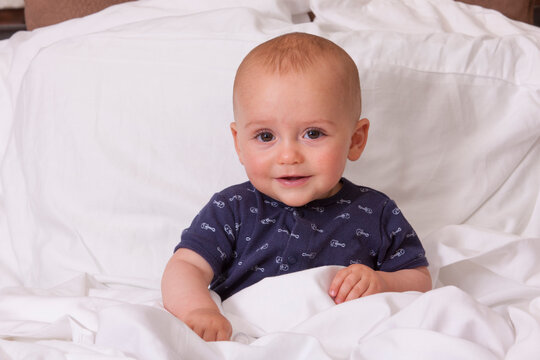 Portrait of a baby boy sitting up in bed