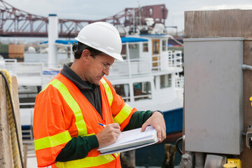 Environmental engineer recording data at ship side in harbor