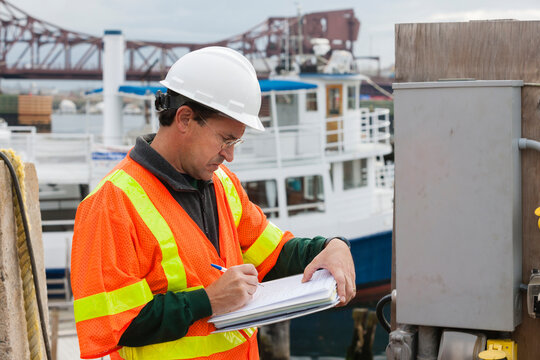 Environmental Engineer Recording Data At Ship Side In Harbor