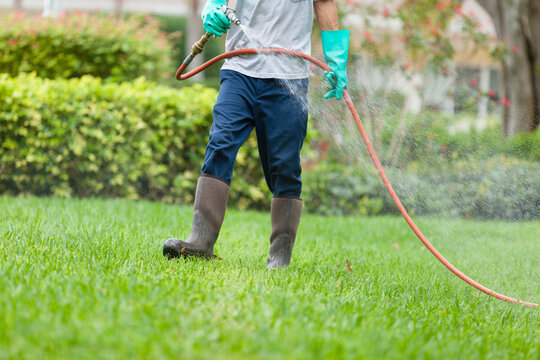Pest control technician using high pressure spray gun and hose with heavy duty gloves