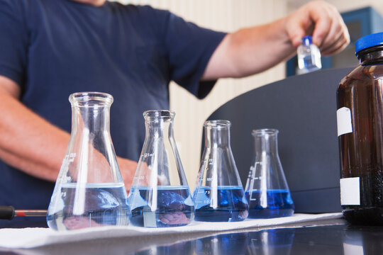 Engineer with sample bottles of indigo solution and ozonated water and vial in hand for analysis in water treatment plant