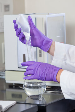 Laboratory scientist adding a premeasured amount of solid reagent to a water sample in a flask