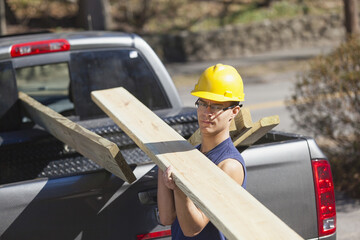 Hispanic carpenter bringing pressure treated wood from truck to job site