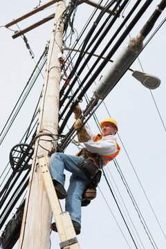 Communications worker positioning new cable on power pole