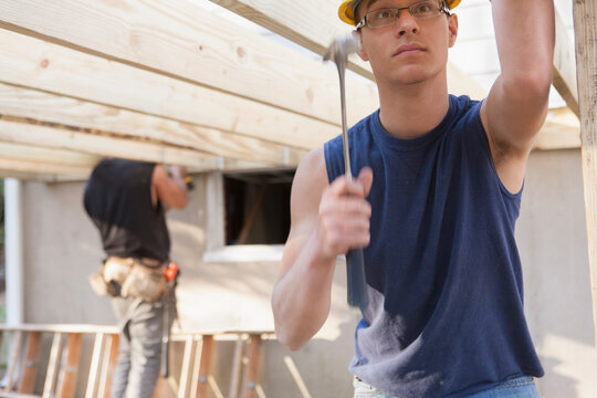 Hispanic carpenter using hammer at home deck construction