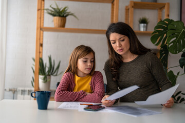 Photo of a young brown hair Caucasian mother helping her elementary age daughter with her homework...