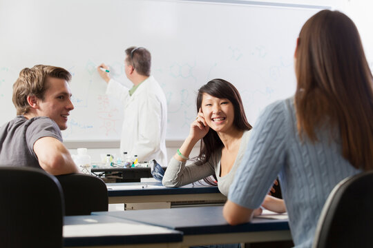 Students talking in an engineering class while the professor is writing on the white board