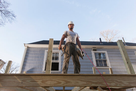Hispanic carpenter using nail gun on home deck construction