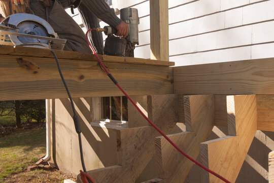 Hispanic carpenter nailing decking at stair stringers