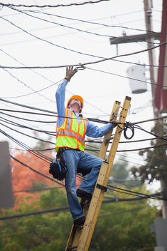 Cable lineman assessing cable splice in the city from ladder