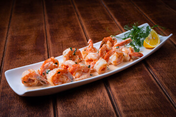 shrimp in lemon sauce in a white plate on a wooden background