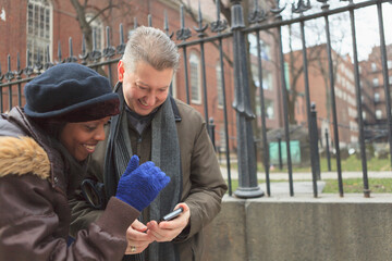 Couple looking at pictures on a cell phone along Tremont Street and The Granary Burying Ground Historic site, Boston, Suffolk County, Massachusetts, USA