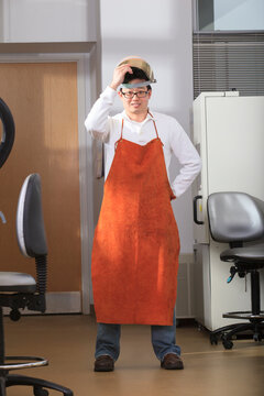 Engineering student wearing leather protective smock and lifting splash guard in chemical analysis laboratory
