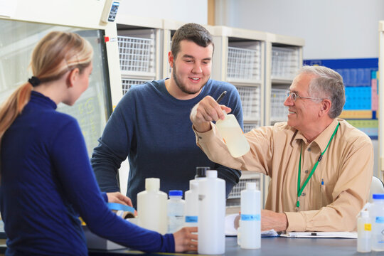 Engineering professor discussing chemical reagents with students in chemical laboratory