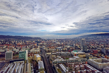 Fototapeta na wymiar Aerial view of City of Zürich seen from industrial district with Lake Zürich and Swiss Alps in the background on a cloudy winter day. Photo taken December 20th, 2022, Zurich, Switzerland.