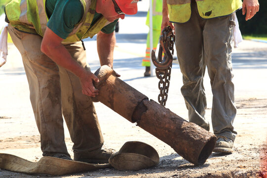 Construction workers inspecting rusted water main section