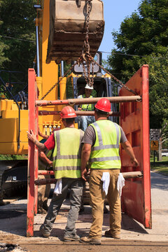 Excavator operator lifting shoring attached to bucket
