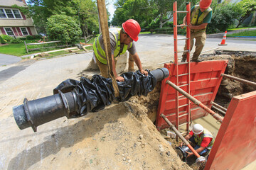 Construction worker preparing to lower water main section