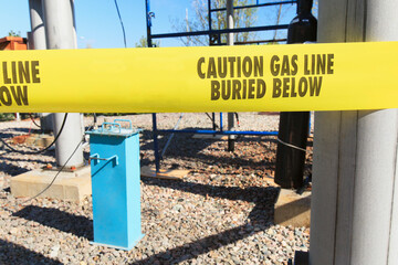 Tape with message 'Caution Gas Line Buried Below' at high voltage distribution station