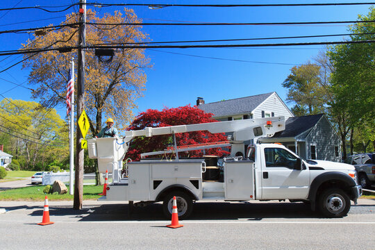 Power engineer in lift bucket with safety equipment for power lines at truck level