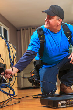 Cable installer working in a home behind the TV